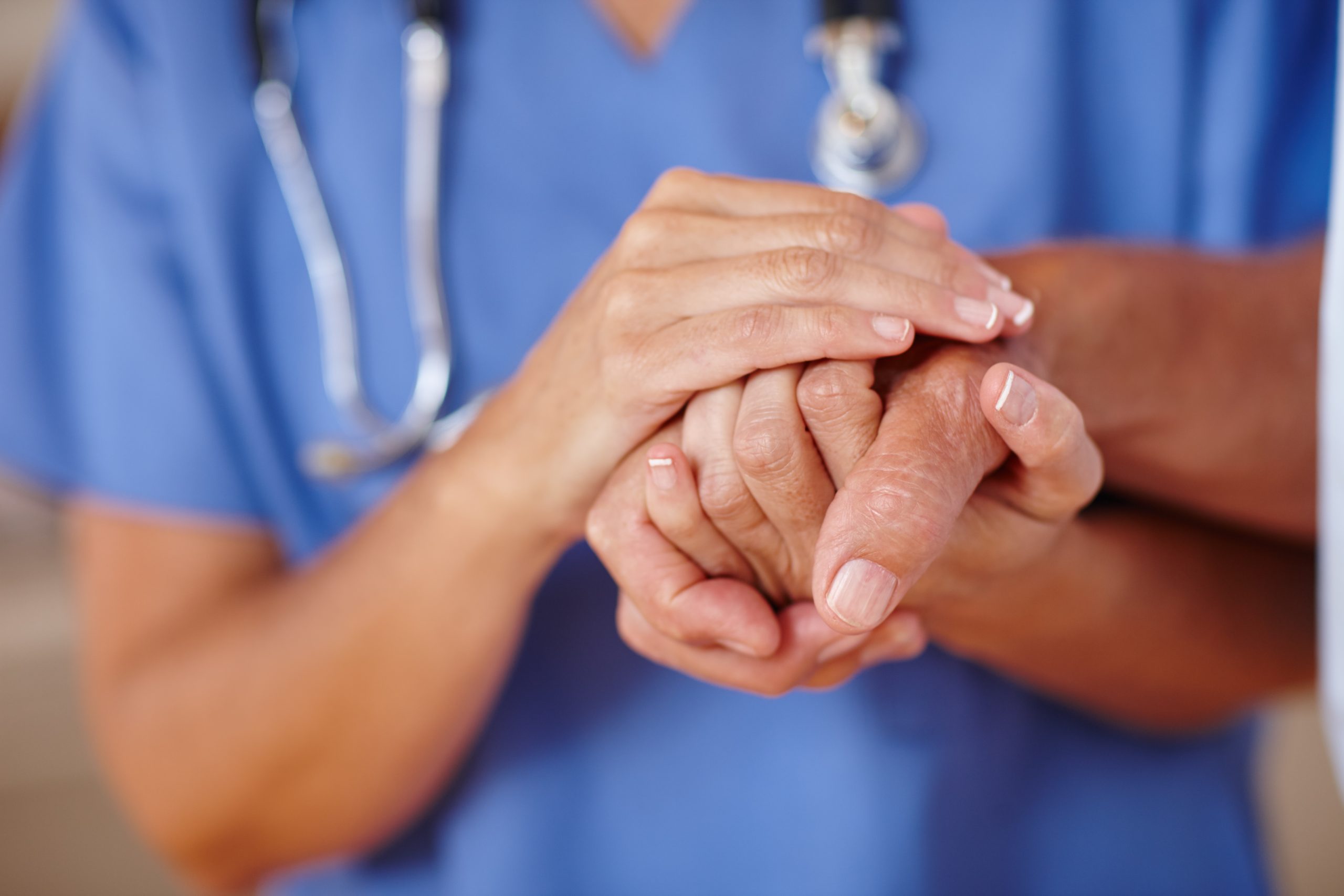 Médico a segurar as mãos de um doente